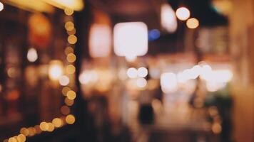 Beautiful bokeh in a dark blurry background at night on the walking street with the people. The round colorful bokeh shine from buildings and shops in the city lifestyle. Abstract concept. video