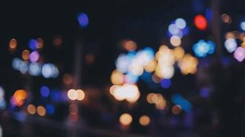 bellissimo bokeh nel un' buio sfocato sfondo a notte su il a piedi strada con il le persone. il il giro colorato bokeh brillare a partire dal edifici e negozi nel il città stile di vita. astratto concetto. video