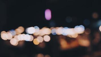 bellissimo bokeh nel un' buio sfocato sfondo a notte su il a piedi strada con il le persone. il il giro colorato bokeh brillare a partire dal edifici e negozi nel il città stile di vita. astratto concetto. video