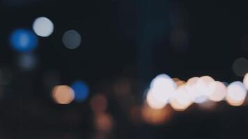 Beautiful bokeh in a dark blurry background at night on the walking street with the people. The round colorful bokeh shine from buildings and shops in the city lifestyle. Abstract concept. video