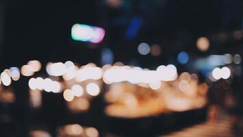 Beautiful bokeh in a dark blurry background at night on the walking street with the people. The round colorful bokeh shine from buildings and shops in the city lifestyle. Abstract concept. video