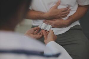 Man suffering with severe stomach pain sitting at home. Hand of mature guy holding abdomen suffering from ache, diarrhea or indigestive problem. Caucasian guy pressing on belly on painful sensation photo