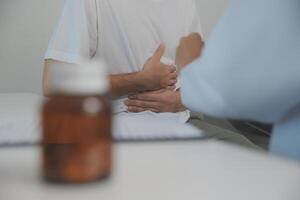 Man suffering with severe stomach pain sitting at home. Hand of mature guy holding abdomen suffering from ache, diarrhea or indigestive problem. Caucasian guy pressing on belly on painful sensation photo