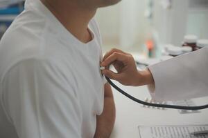 joven médico es utilizando un estetoscopio escucha a el latido del corazón de el paciente. Disparo de un hembra médico dando un masculino paciente un cheque arriba foto