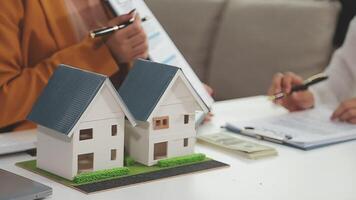 discusión con un agente de bienes raíces, modelo de casa con agente y cliente discutiendo el contrato para comprar, obtener seguros o préstamos de bienes raíces o propiedades. video