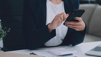 el mujer trabajos a hogar y usos un inteligente teléfono y un cuaderno ordenador portátil computadora. silueta de un ocupado mujer. ella sostiene y utilizando teléfono. video