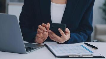 el mujer trabajos a hogar y usos un inteligente teléfono y un cuaderno ordenador portátil computadora. silueta de un ocupado mujer. ella sostiene y utilizando teléfono. video