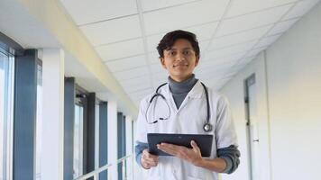 Indian male physician or intern professional general practitioner posing with stethoscope looking at camera in clinic video