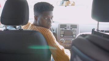 African american driver looks around the back seat while driving an electric car video