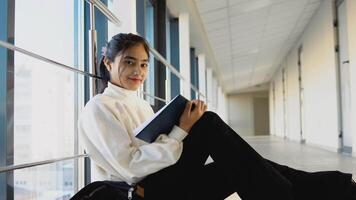 indiano menina aluna sentado em a chão com uma livros dentro a universidade ou faculdade. Novo moderno totalmente funcional Educação instalação. conceito do conectados Educação video