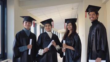 Indian university graduates stand in front of the camera in master's hats and black robes video