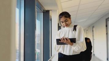 indio mujer estudiante con un tableta en el universidad. nuevo moderno completamente funcional educación instalación. concepto de en línea educación video