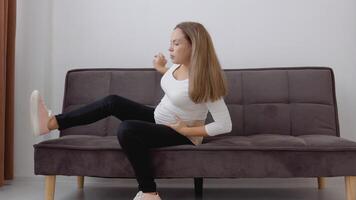 Pregnant fair-skinned woman in a bandage belt tries to get up from the couch video