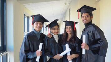 Indian university graduates stand in front of the camera in master's hats and black robes video