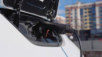 Electric car charging batteries with electricity through power cable on parking lot in a residential area video