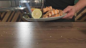 The chef pours oil on fried fish, tomatoes, lemon, vegetables lying on the plate video