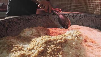 The chef stirs steaming rice in a large pilaf cauldron with a slotted spoon video