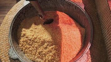 The chef stirs steaming rice in a large pilaf cauldron with a slotted spoon video