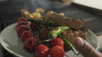 le chef les transferts frit poisson, tomates et des légumes de le gril à une assiette video