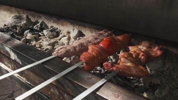 A kebab maker puts kebabs of chicken, meat, liver and vegetables on the grill with coals. video