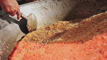 The chef stirs steaming rice in a large pilaf cauldron with a slotted spoon video