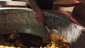 The chef puts carrots with a slotted spoon in a plate with rice from a large cauldron for pilaf video