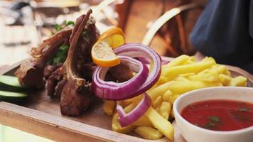 The chef demonstrates a wooden board served with cooked meat, onions, herbs, tomatoes and vegetables video