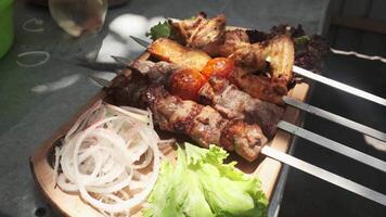 The chef serves kebabs with chicken, cape and liver on a wooden board with onions, herbs, tomatoes and vegetables. video