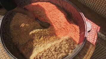 The chef tosses rice with a slotted spoon in a large cauldron while cooking pilaf video