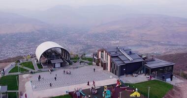 The drone flies around the mountain station of the cable car with a restaurant next to it. Against the background of the sunset sky video