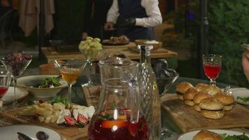 Table setting by a waiter in a night open cafe surrounded by trees and fir trees video