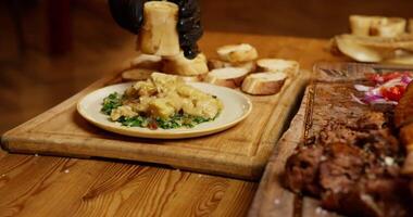 The waiter cuts the finished meat and runs the table in the restaurant video