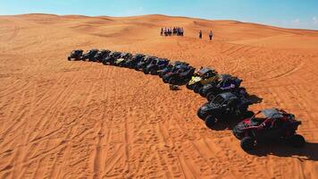 Dubai, UAE - 1 14 2023. A drone flies over a caravan of buggies standing on a desert sand dune. video