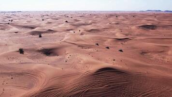 A drone flies over a caravan of buggies driving through the desert sand video