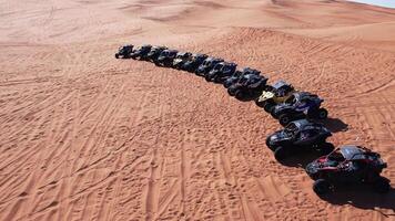 un zumbido moscas terminado un caravana de buggies en pie en un Desierto arena duna. video