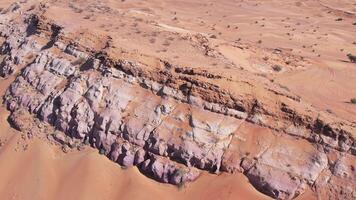 A drone flies over a lonely rock among the sand dunes of the desert video