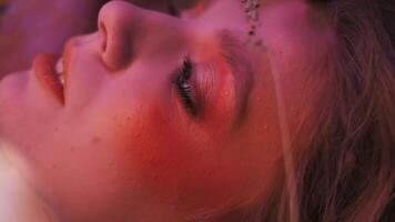 Macro shot of the face of a young woman in an autumn outfit of branches, leaves and ears of corn, flying in the grass among scattered apples. video