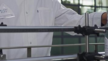 A man in a white coat checks water bottles on a conveyor belt video