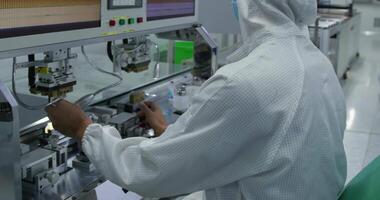 An operator in a protective gown works on an assembly line for the production of electronic devices. video