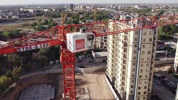 Taskent, Uzbekistán - 8 4 4 2022. zumbido moscas terminado construcción grua entre Departamento edificios debajo construcción en verano día video