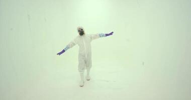 Man in white chemical protection suite dances on the light background video