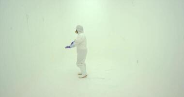 Man in white chemical protection suite dances on the light background video