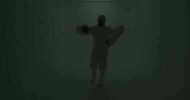 Strange silhouette of man in chemical protection suite with very long sleeves video