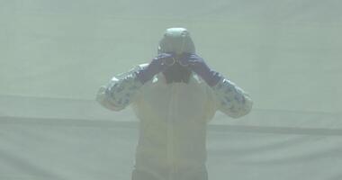 Man in white chemical protection suit takes off his glasses video