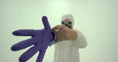 man in white chemical protection suit puts on protective gloves video