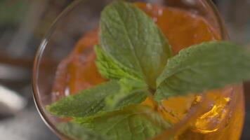 närbild av orange cocktail med mynta löv och is i de glas video