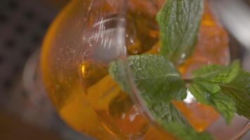 detailopname van oranje cocktail met munt bladeren en ijs in de glas video