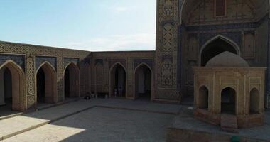 de dar vliegt in de omgeving van de binnenplaats van de oude complex lyab-ik haas met toeristen Aan het. oud bukhara, Oezbekistan. video