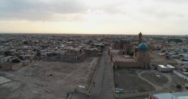 A drone flies over the architectural complex Poi-Kalon among old houses in Bukhara, Uzbekistan. Early cloudy morning video