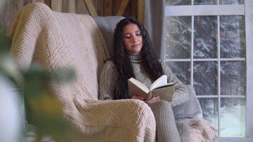 familie kerstmis, pret partij, blijven Bij huis, nieuw jaar viering. gelukkig vrouw lezing boek Bij huis terwijl zittend in de buurt Kerstmis boom video